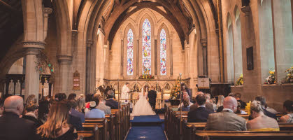 A wedding couple, their guests and the rector, viewed from the west end of Holy Trinity Church, Leaton
