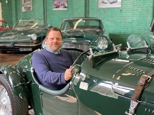 Adam seated in a vintage, open-topped racing car