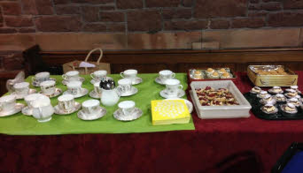 A table of delicate tea cups and saucers, together with an enticing selection of tasty cakes