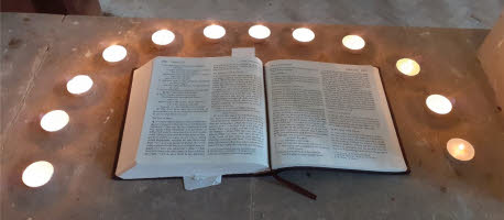 An open bible surrounded by lit tealights